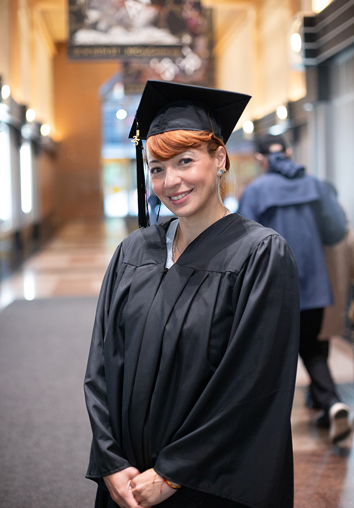 student smiles for a photo in cap and gown